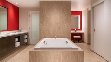 Un baño moderno con una bañera independiente, un tocador con espejo y un taburete.
