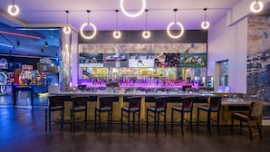 A bar area with multiple gaming machines, bar stools, and a large screen displaying sports events. - Horseshoe Las Vegas (Las Vegas)