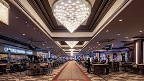A spacious casino area with a central walkway, multiple gaming tables, and a large chandelier. - Horseshoe Las Vegas (Las Vegas)