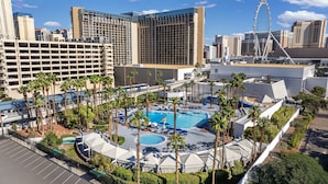 A hotel with a large outdoor pool surrounded by palm trees, a parking garage, and modern buildings in the background. - Horseshoe Las Vegas (Las Vegas)
