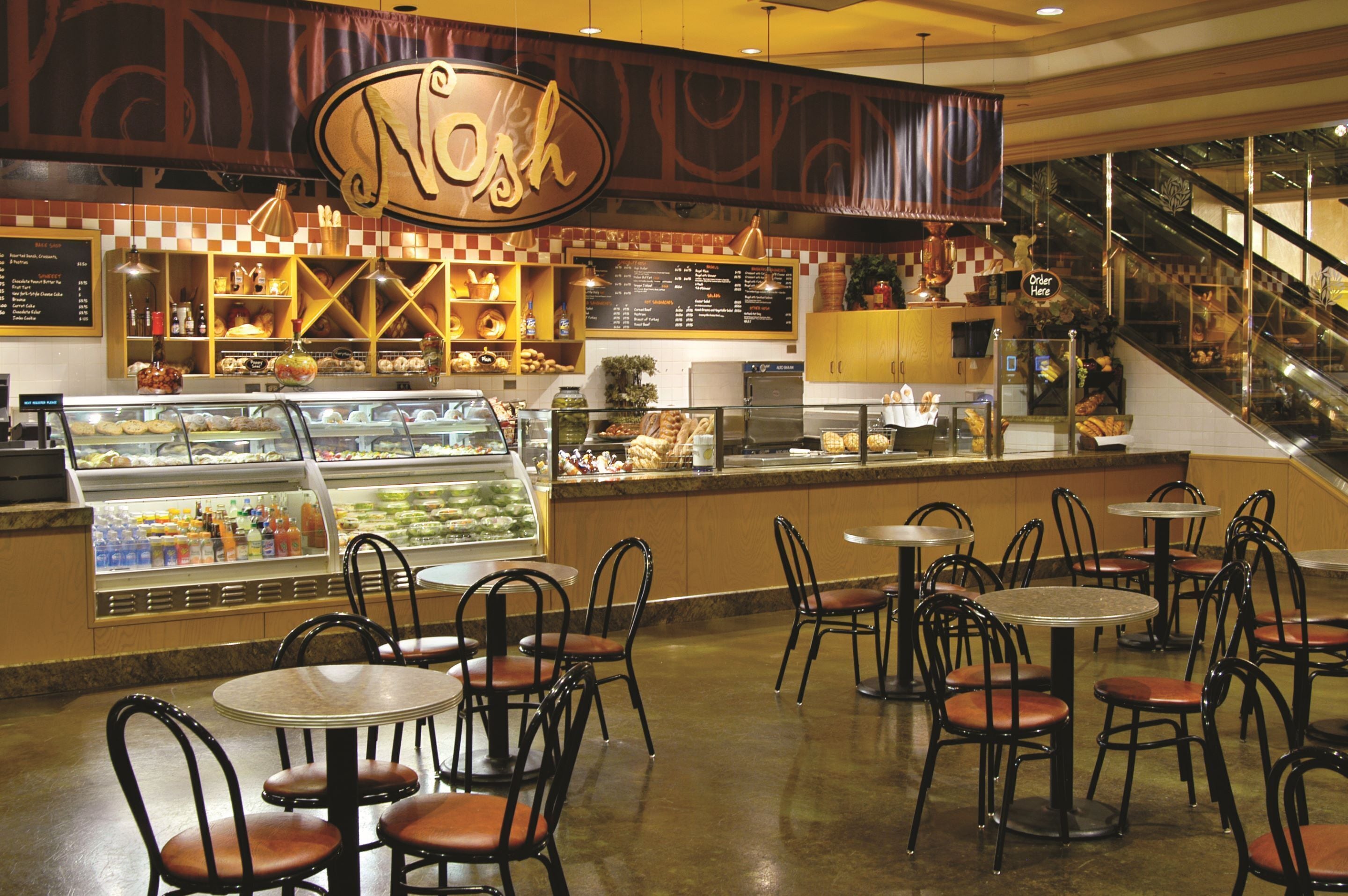 A bakery with a display case, counter, and seating area with tables and chairs.