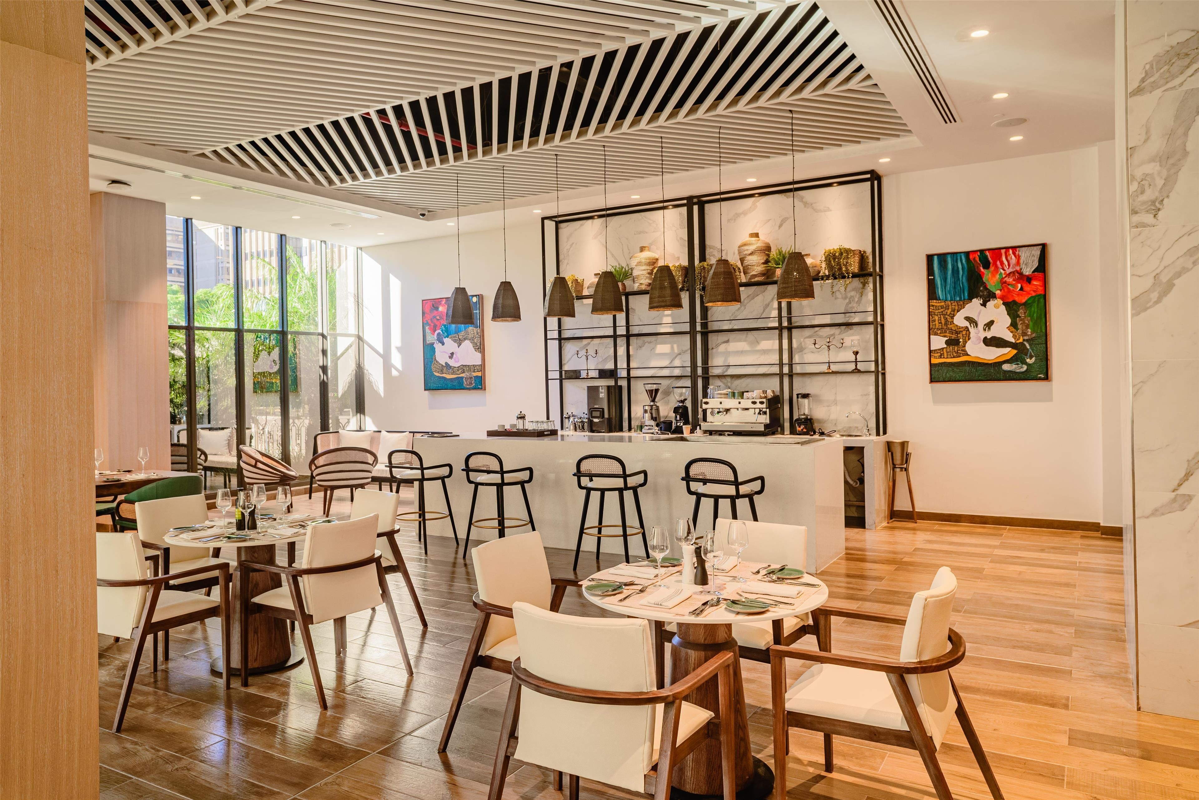 Un espace de restauration moderne avec des tables rondes, des chaises et des luminaires suspendus.