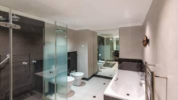 Un baño moderno con ducha envuelta en vidrio, bañera independiente y retrete separado.