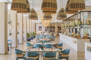 Ruime eethoek met meerdere tafels en stoelen, een centraal hanglamp en een presentatie van decoratieve vazen aan de rechterkant.