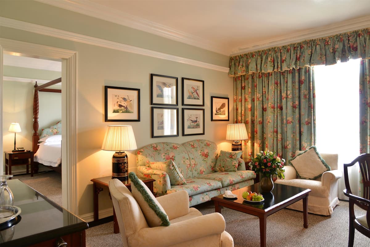 A living room with a sofa, armchairs, a coffee table, and framed artwork on the wall.