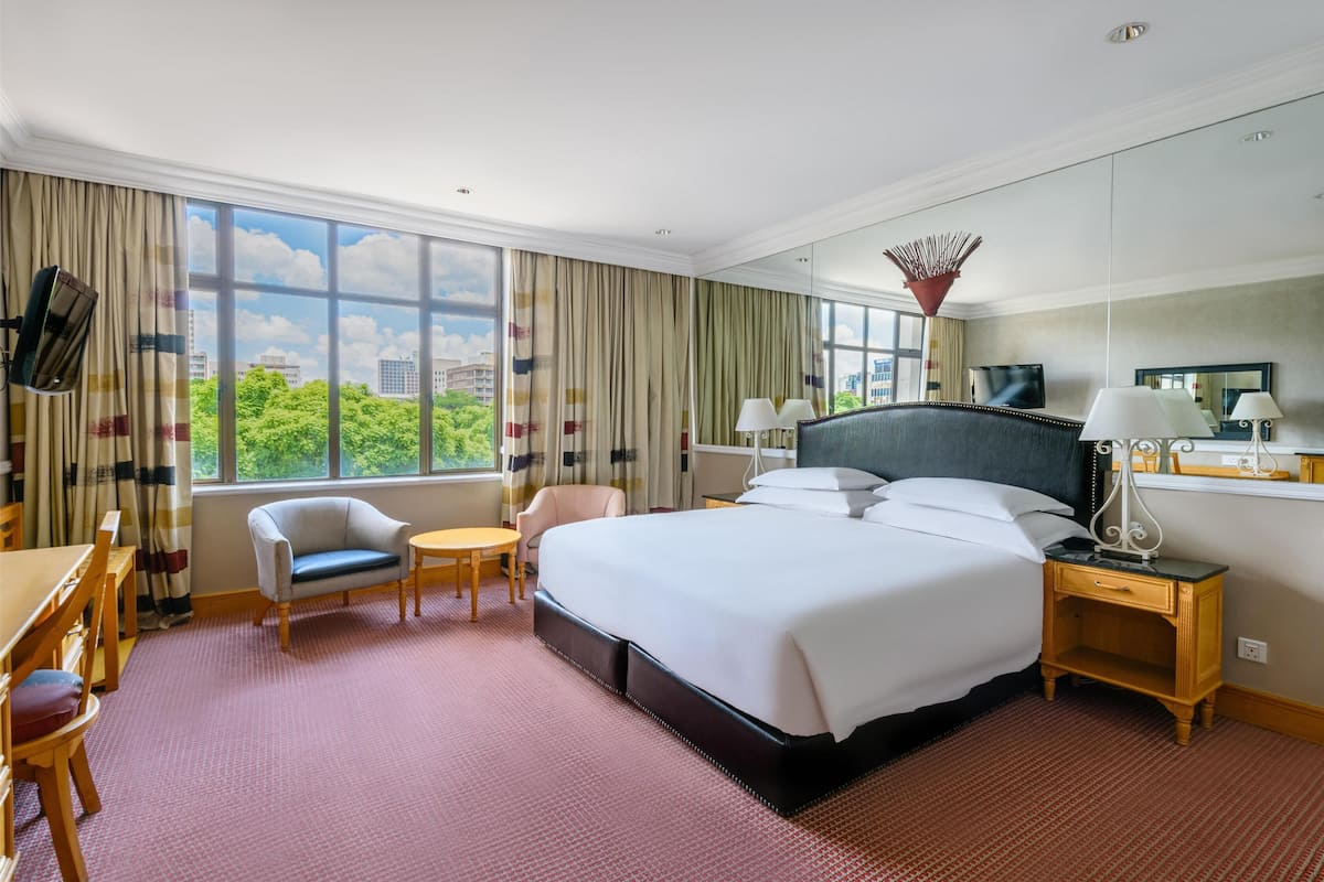 A hotel room with a large bed, a desk, a chair, and a TV.
