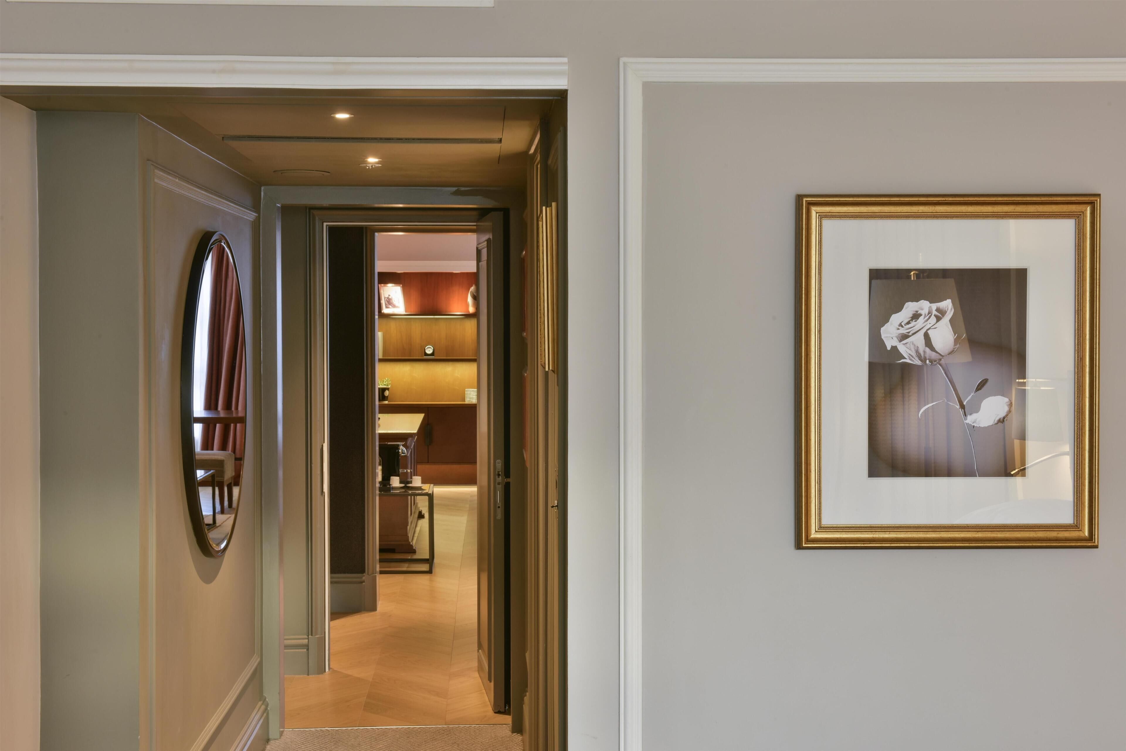 A hallway with a framed picture of a white rose on the wall.