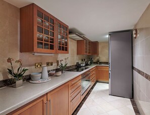 A kitchen with wooden cabinets, a stainless steel refrigerator, and a marble countertop. - Hyatt Regency London The Churchill (London)