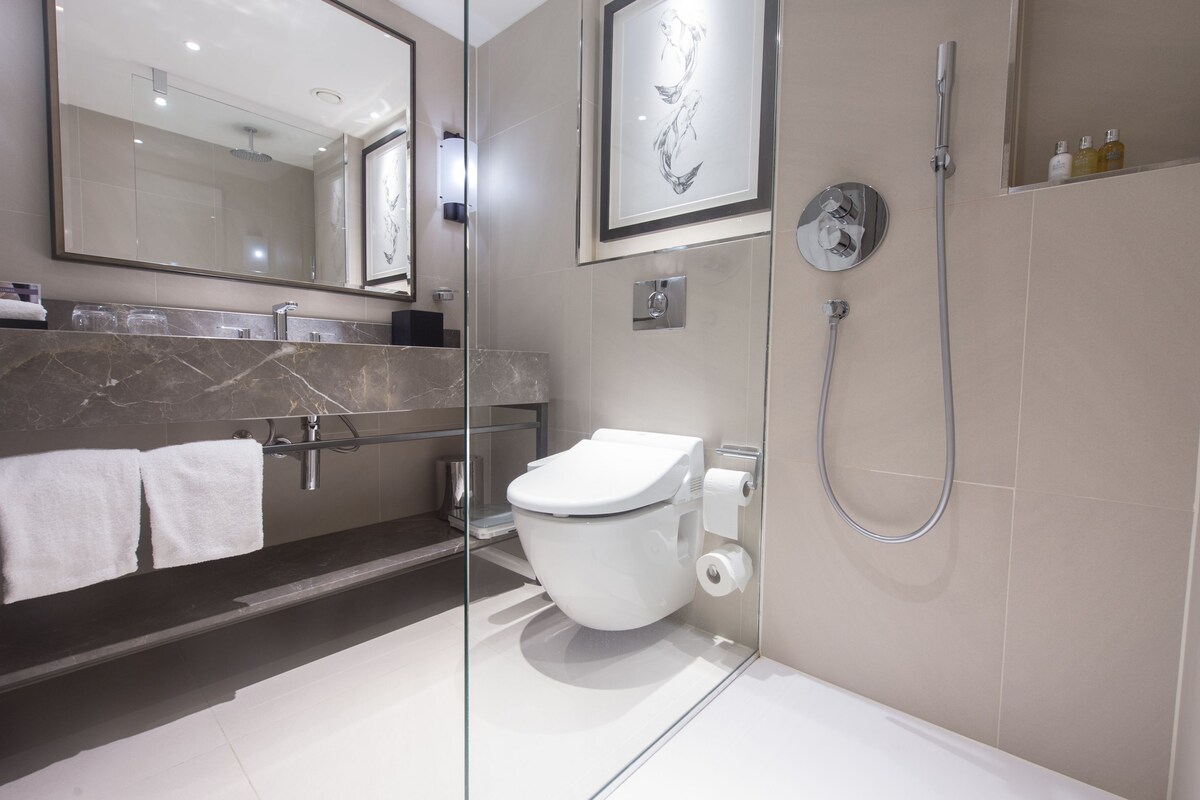 A modern bathroom with a glass partition, a white toilet, a shower, and a marble countertop.