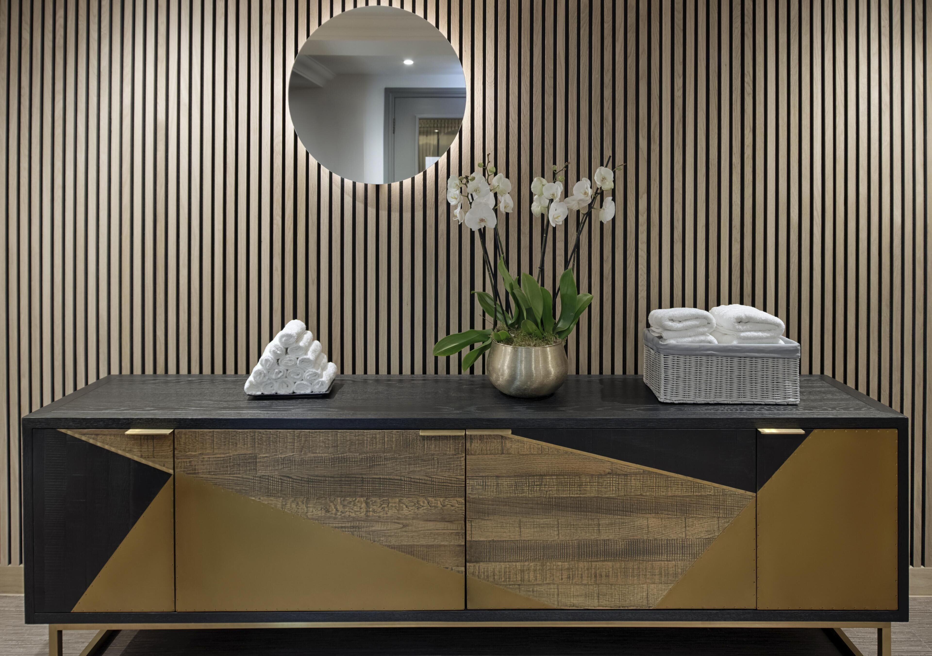 A modern bathroom vanity with a mirror, a potted orchid, and neatly folded towels.