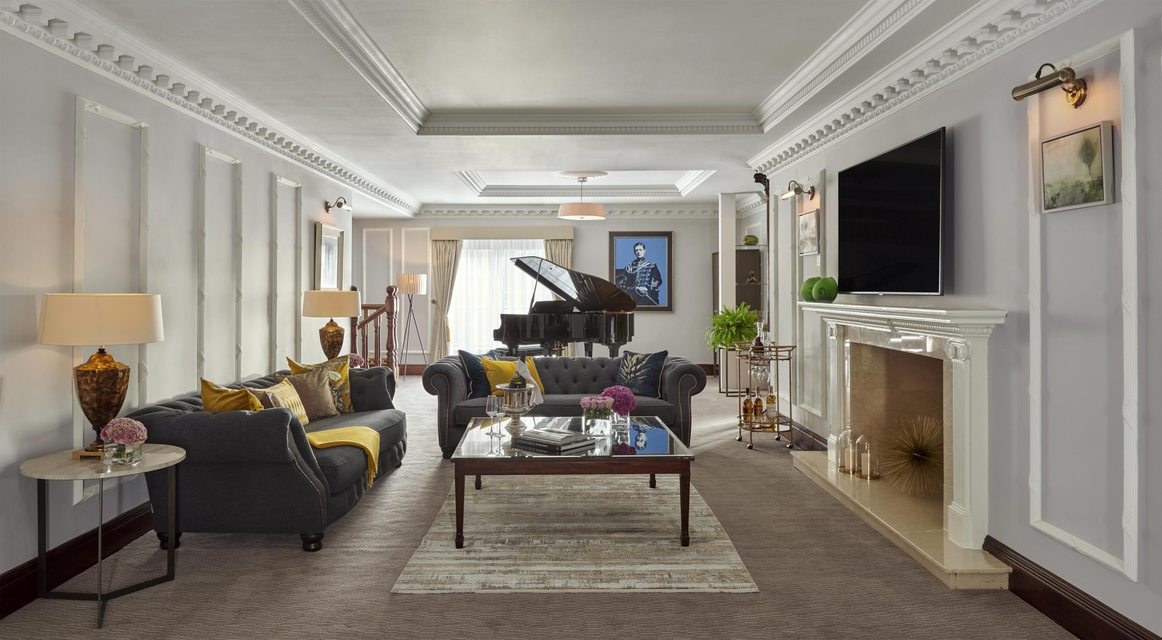 A spacious living room with a grand piano, a fireplace, and a television mounted on the wall.