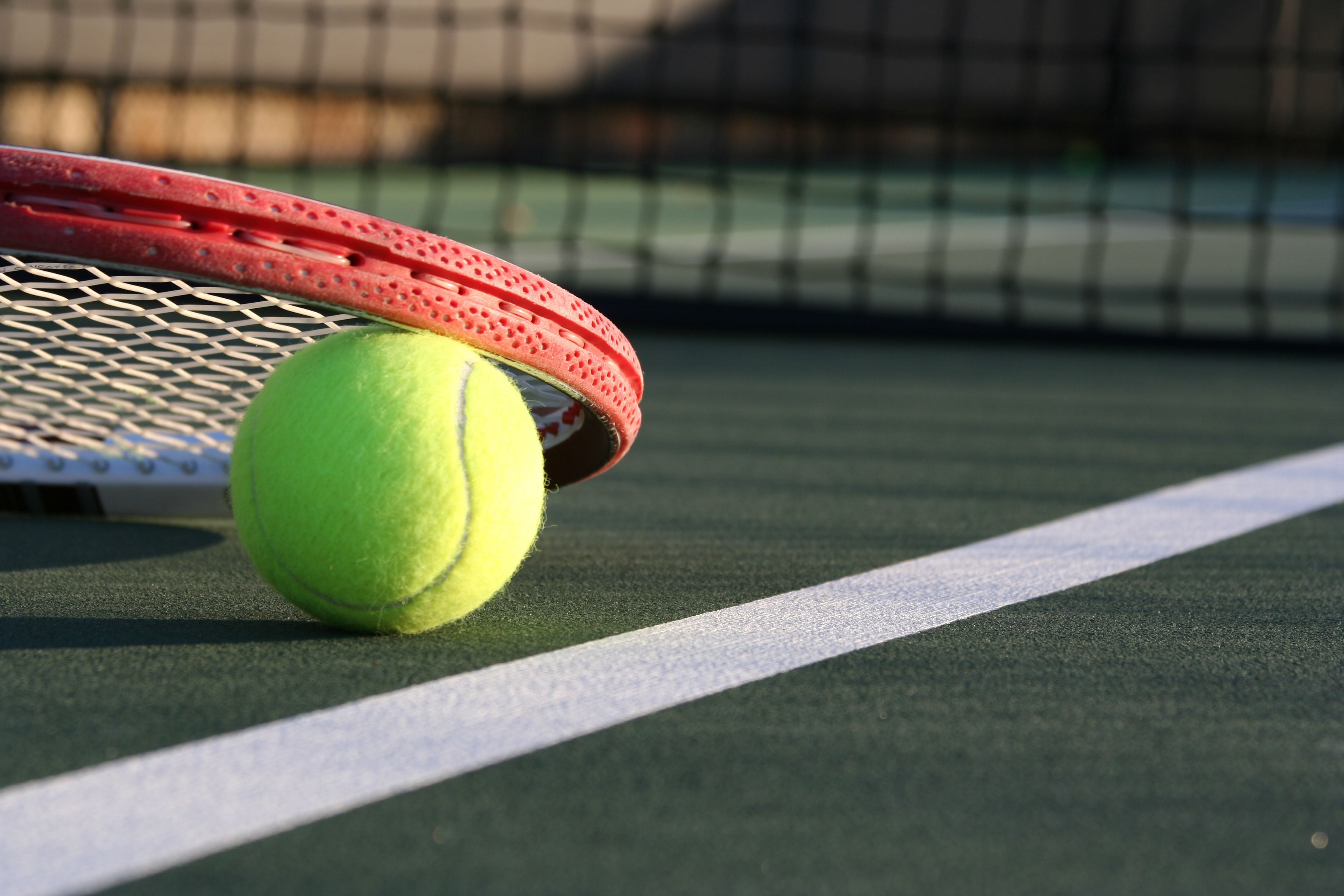 A tennis ball and racket on a court.