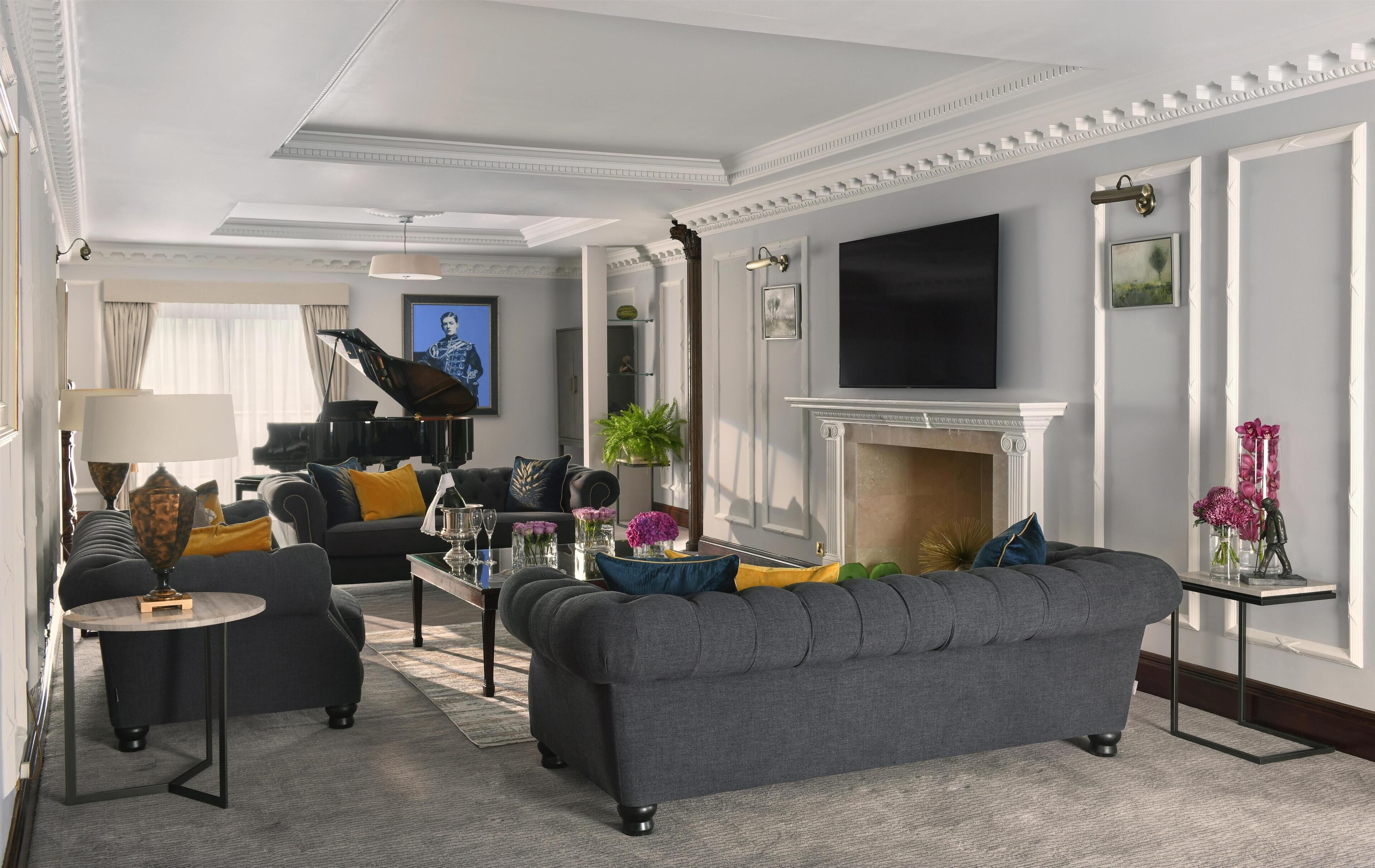 A spacious living room with a grand piano, a comfortable sofa, a flat-screen TV, and a fireplace.