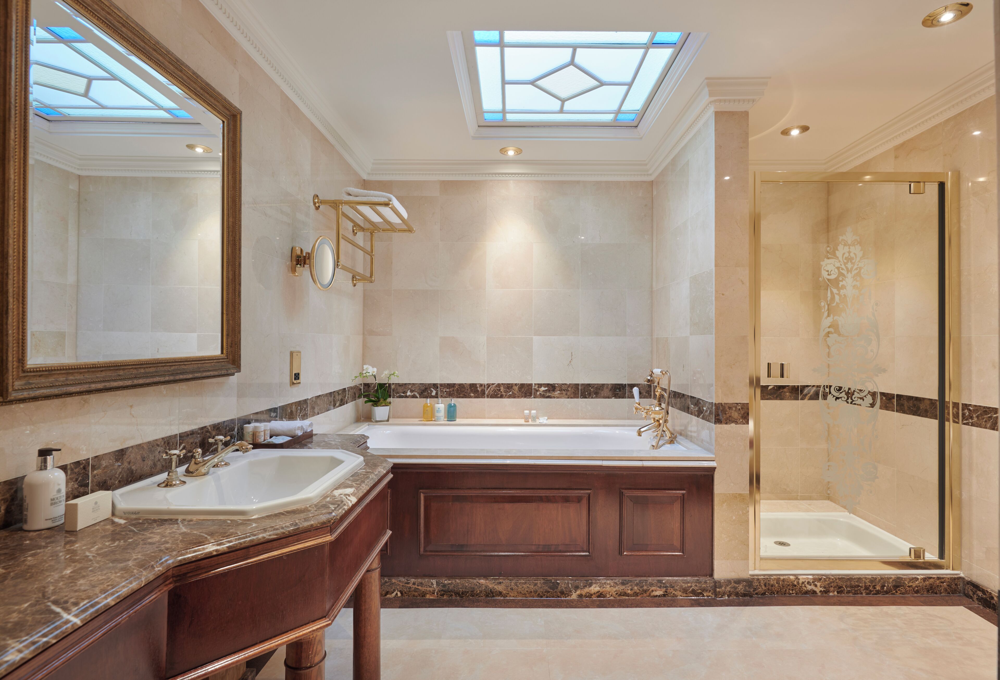 A luxurious bathroom with a skylight, a large bathtub, a separate shower area, and marble countertops.
