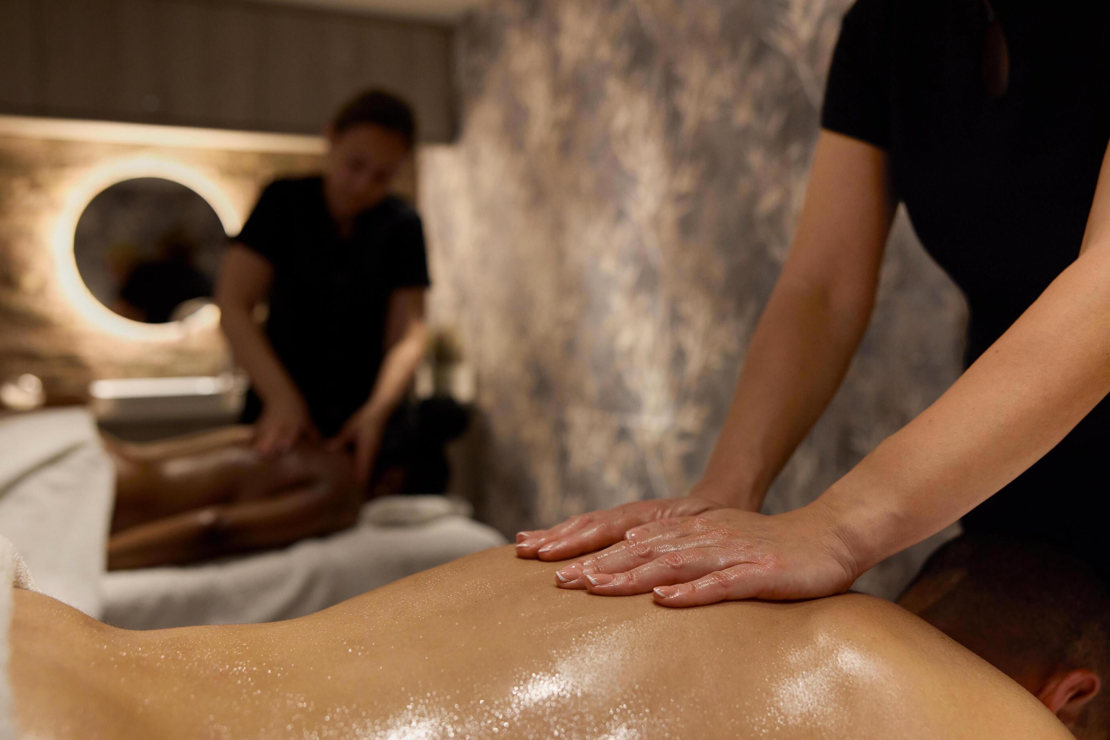 Sesión de terapia de masajes en un spa, con una camilla y una silla de masaje circular al fondo.