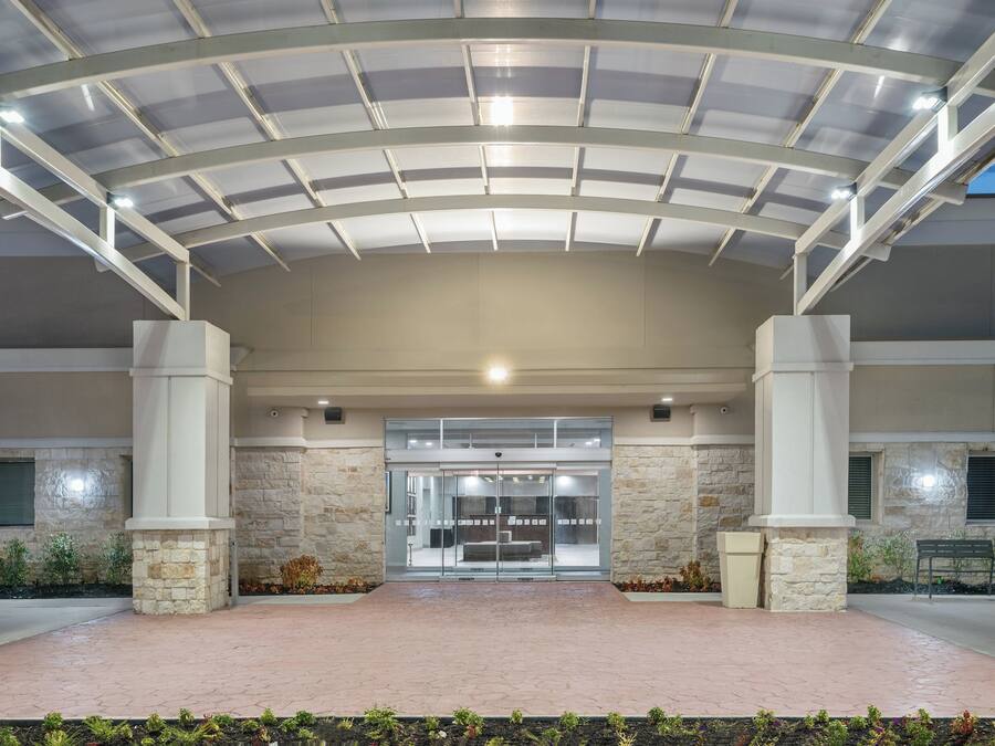 A covered entrance with a glass door, stone pillars, and a paved walkway.