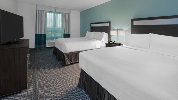 A hotel room with two beds, a TV, a desk, and a window with curtains. - Holiday Inn Beaumont East - Medical Ctr Area by IHG (Beaumont)