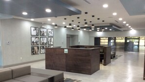 A modern lobby with a reception desk, seating area, and artwork on the walls. - Holiday Inn Beaumont East - Medical Ctr Area by IHG (Beaumont)