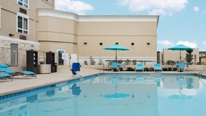 A pool area with lounge chairs and umbrellas, a building with a beige facade, and a clear sky. - Holiday Inn Beaumont East - Medical Ctr Area by IHG (Beaumont)