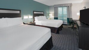 A hotel room with two beds, a desk, a television, and a window with curtains. - Holiday Inn Beaumont East - Medical Ctr Area by IHG (Beaumont)
