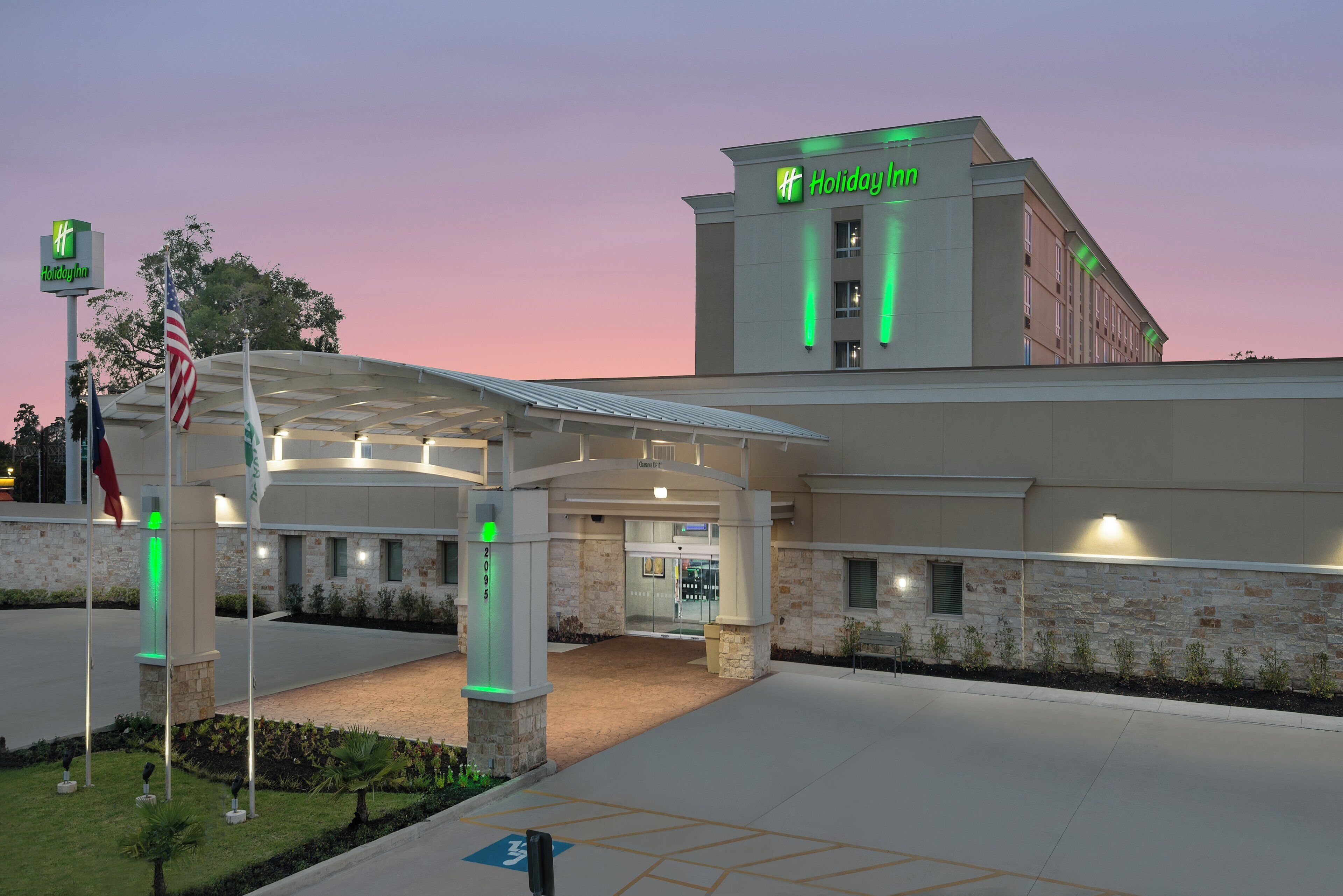 L’entrée d’un hôtel Holiday Inn, avec une allée couverte et une façade en pierre.
