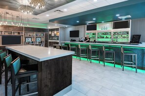 Un espace bar avec un comptoir, des tabourets et un barman.
