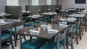 A restaurant with multiple tables and booths, each equipped with table settings and chairs. - Holiday Inn Beaumont East - Medical Ctr Area by IHG (Beaumont)