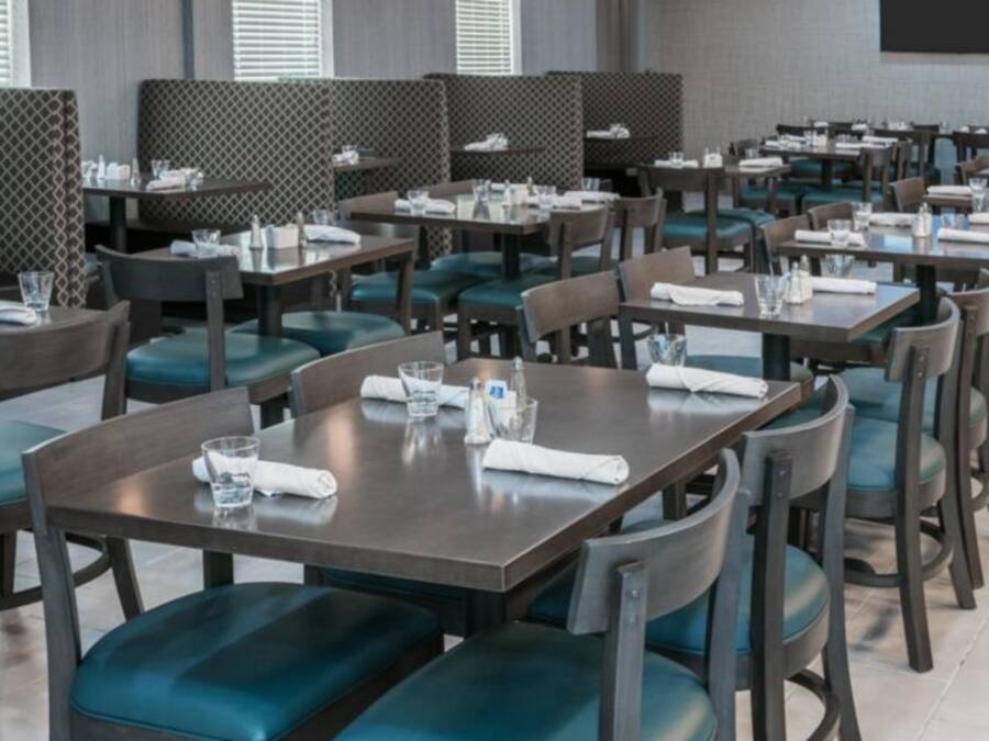 Een restaurant met meerdere tafels en zitbanken, elk met servies en stoelen.
