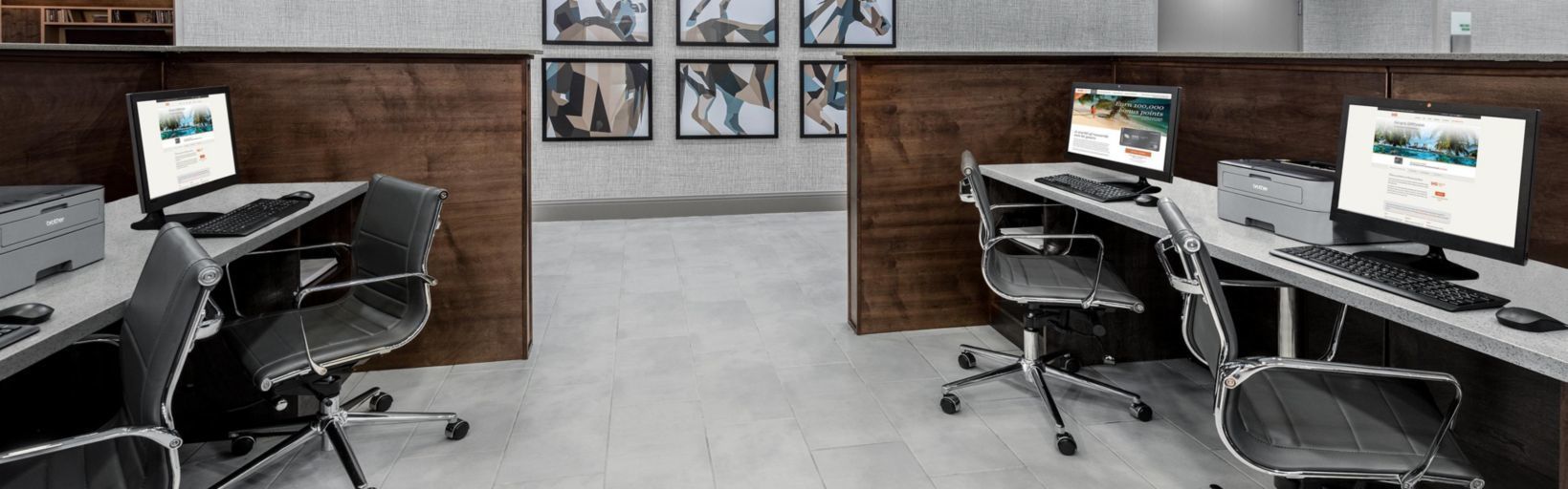 A modern office space with two desks, each with a computer, keyboard, and chair.