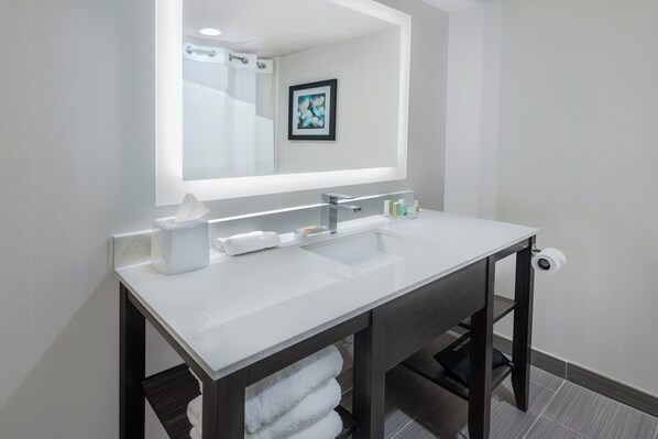 A modern bathroom with a white sink, a large mirror, and a framed picture on the wall. - Holiday Inn Beaumont East - Medical Ctr Area by IHG (Beaumont)