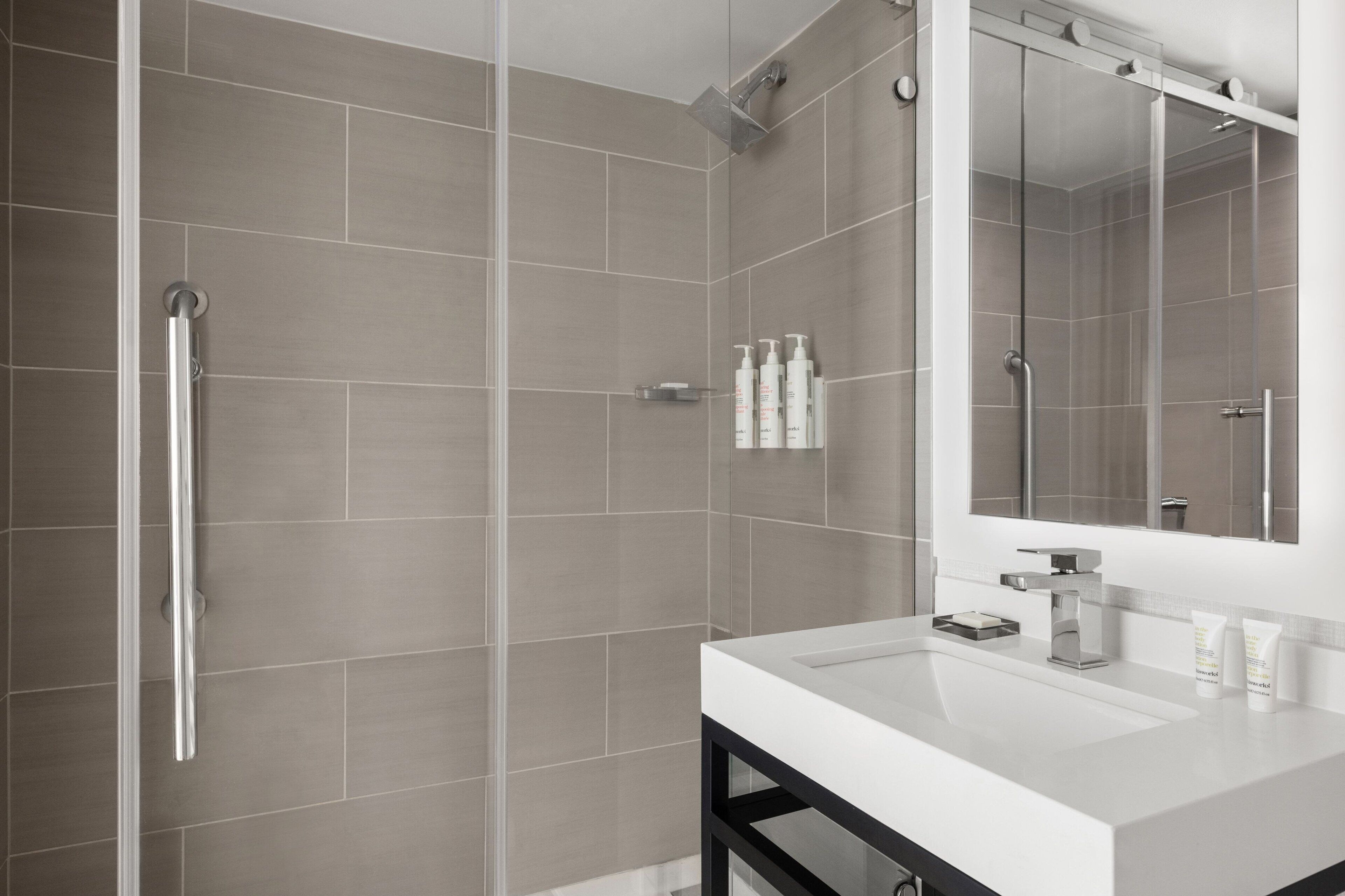 Un baño moderno con ducha, lavamanos y espejo.