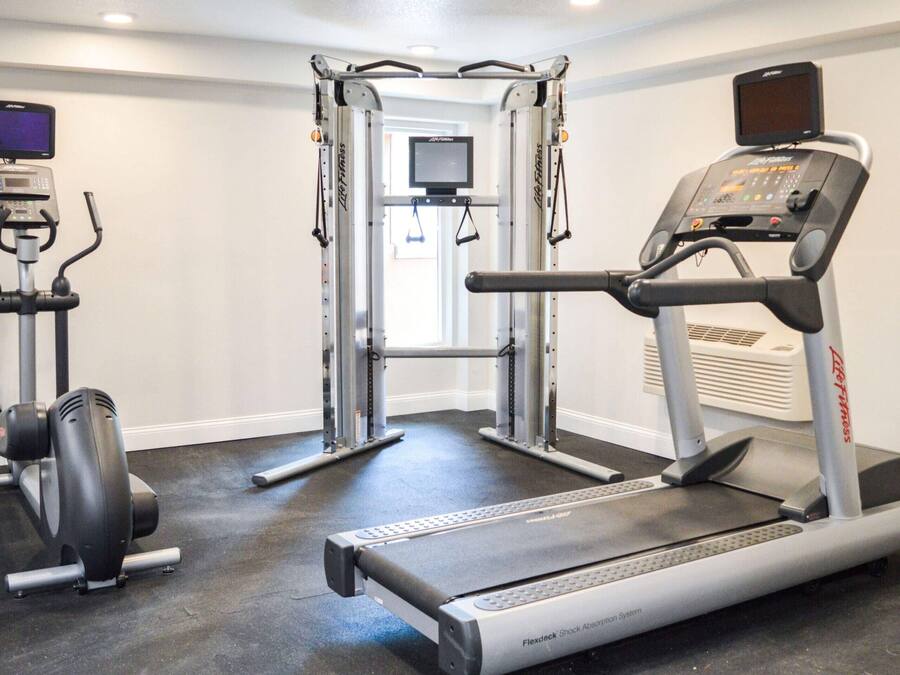 Une salle de sport équipée d’un tapis de course, d’appareils de musculation et d’une barre de traction.