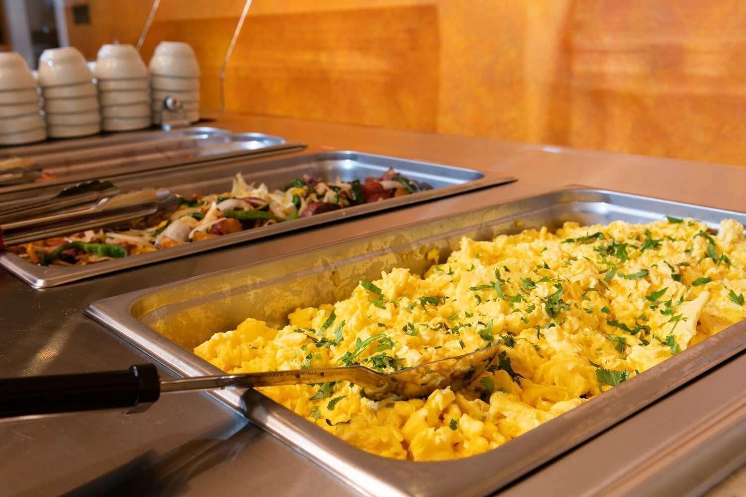 Un buffet proposant des œufs brouillés et une salade.