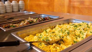 Un buffet proposant des œufs brouillés et une salade.
