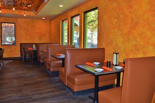A restaurant with booths and tables, wooden flooring, and large windows.