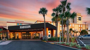 A Radisson hotel with a modern facade, palm trees, and a parking lot. - Radisson Hotel Orlando Lake Buena Vista South (Kissimmee)