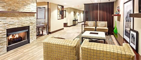 A lobby with a stone fireplace, patterned chairs, a coffee table, and a wooden partition.