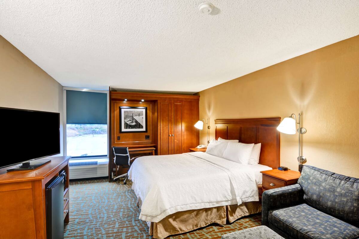 Ein Hotelzimmer mit einem großen Bett, einem Fernseher, einem Schreibtisch und einem Stuhl.