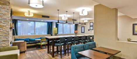 A hotel lobby with a bar area, seating, and a stone accent wall.