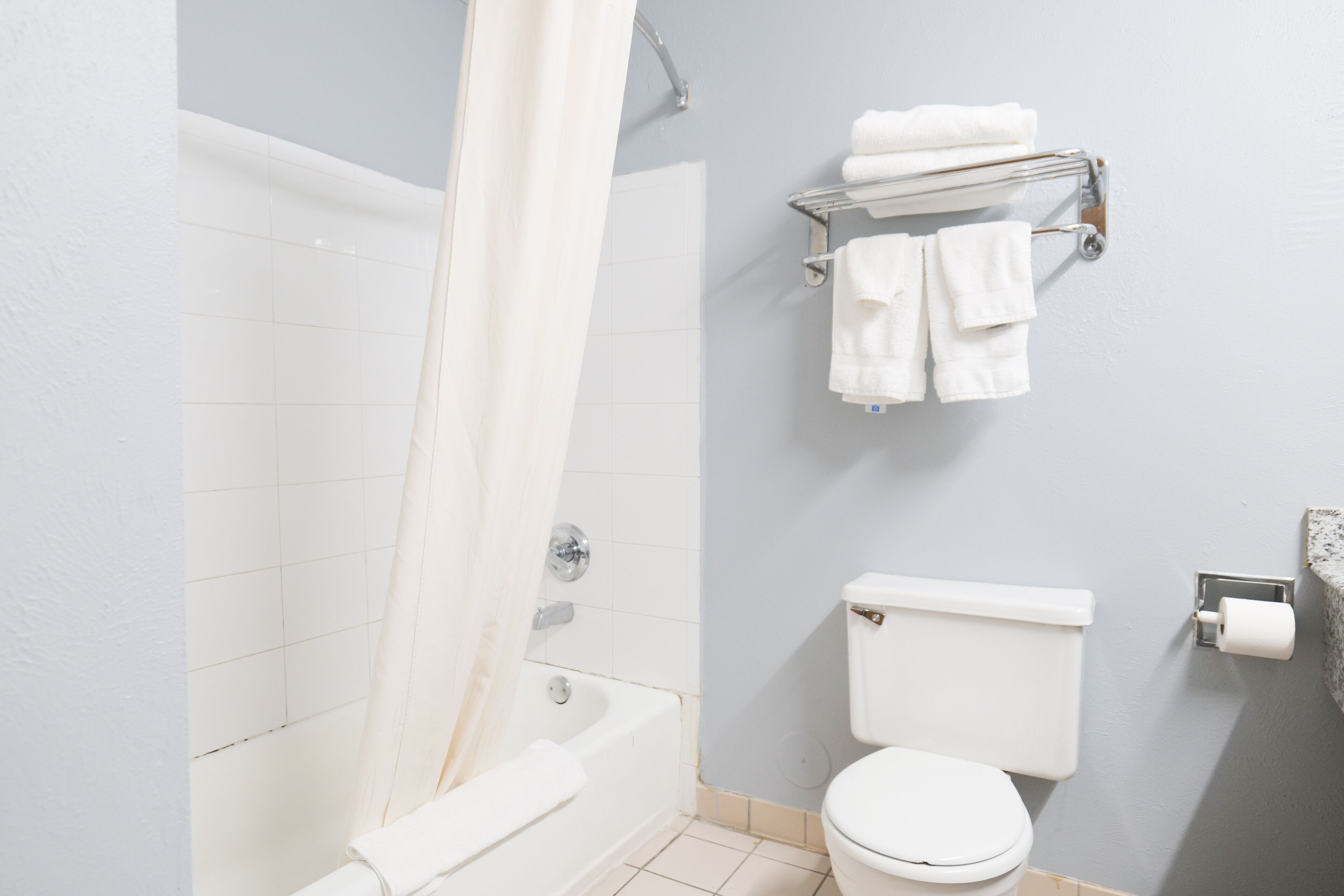 A bathroom with a bathtub, toilet, and towel rack.