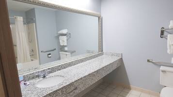 A bathroom with a granite countertop sink, a large mirror, a towel rack, and a shower curtain.