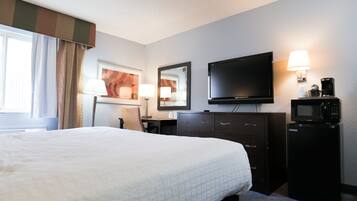 Habitación de hotel con una cama grande, un escritorio, un televisor de pantalla plana, un microondas y una cafetera.