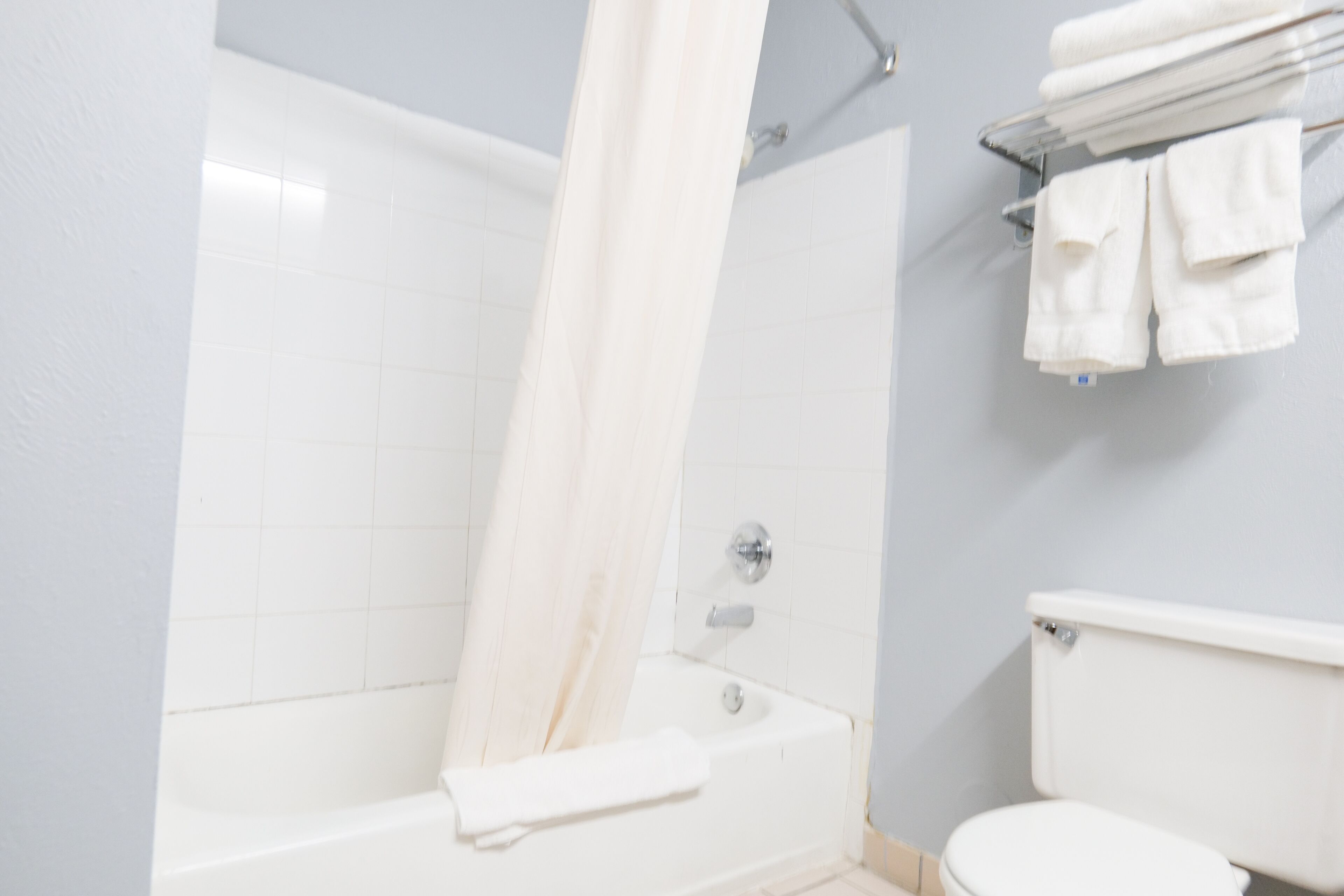 A bathroom with a bathtub, a shower curtain, and a toilet.