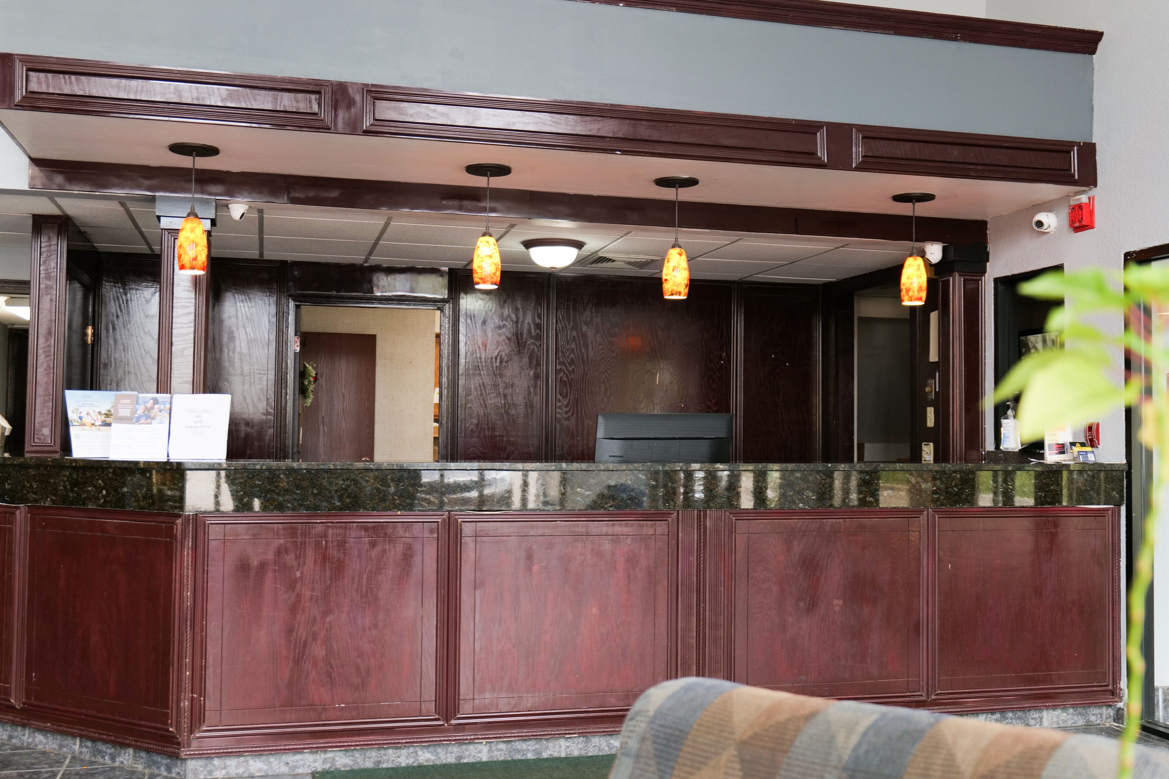 A reception area with a marble counter, wooden paneling, and pendant lighting.