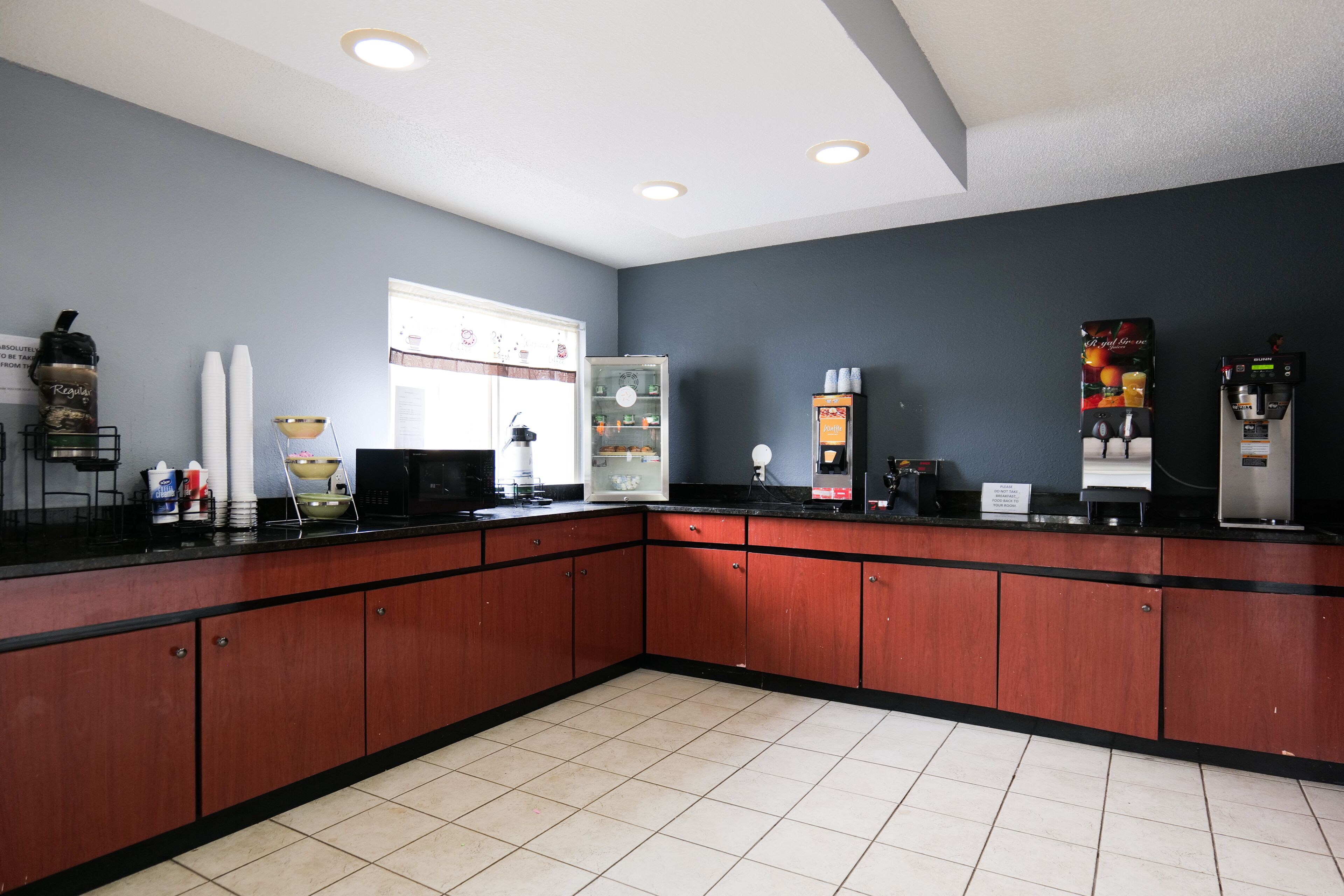 A kitchen with a black countertop, wooden cabinets, and a refrigerator.