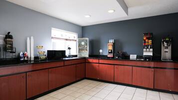 A kitchen with a black countertop, wooden cabinets, and a refrigerator.