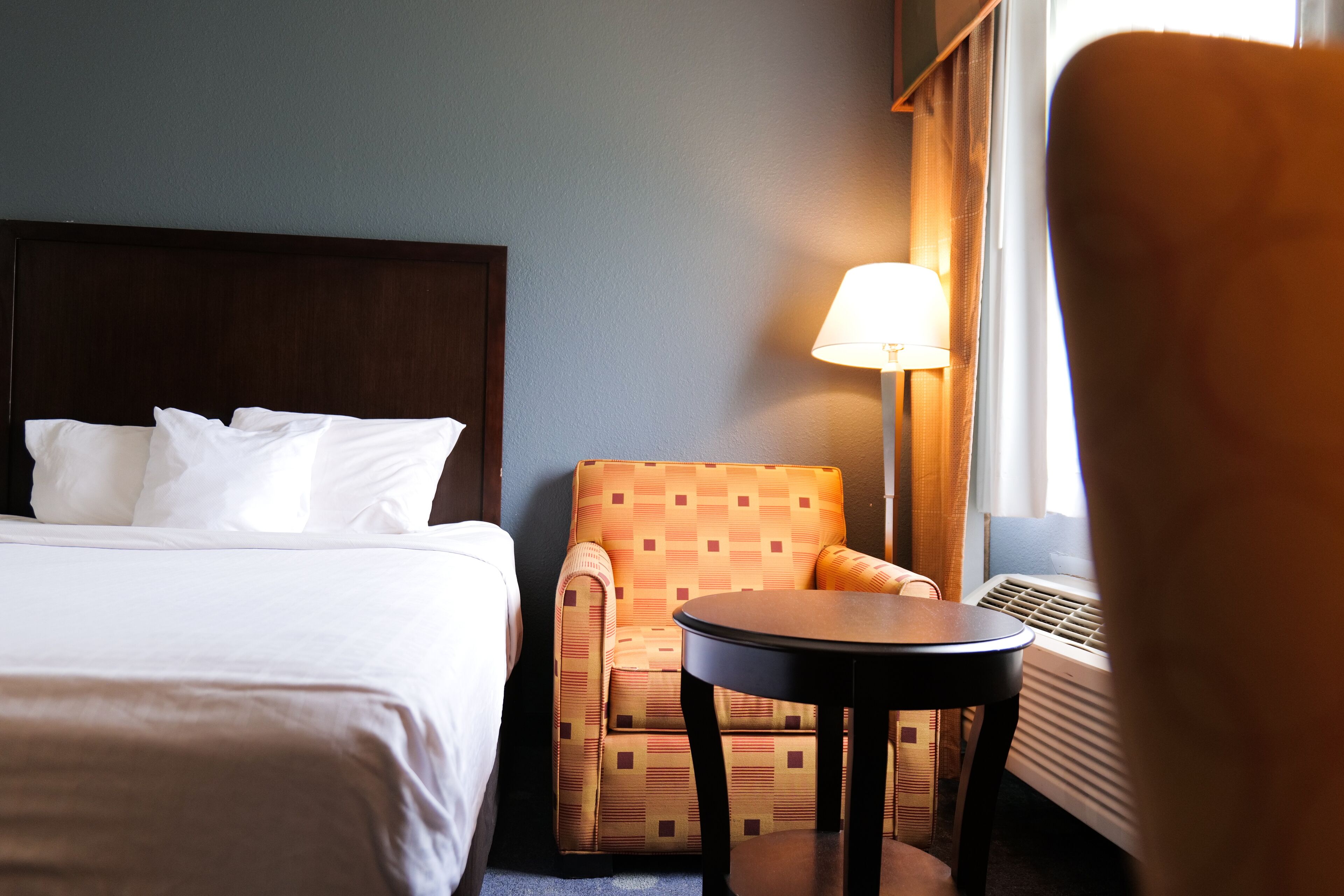 Une chambre d’hôtel avec un lit, une chaise, une table et une lampe.