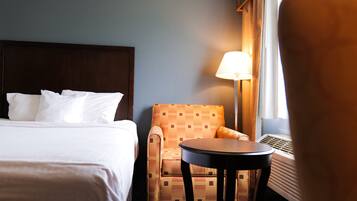 Une chambre d’hôtel avec un lit, une chaise, une table et une lampe.