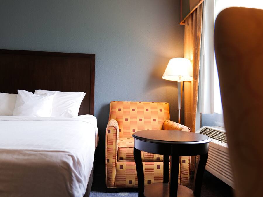 Une chambre d’hôtel avec un lit, une chaise, une table et une lampe.