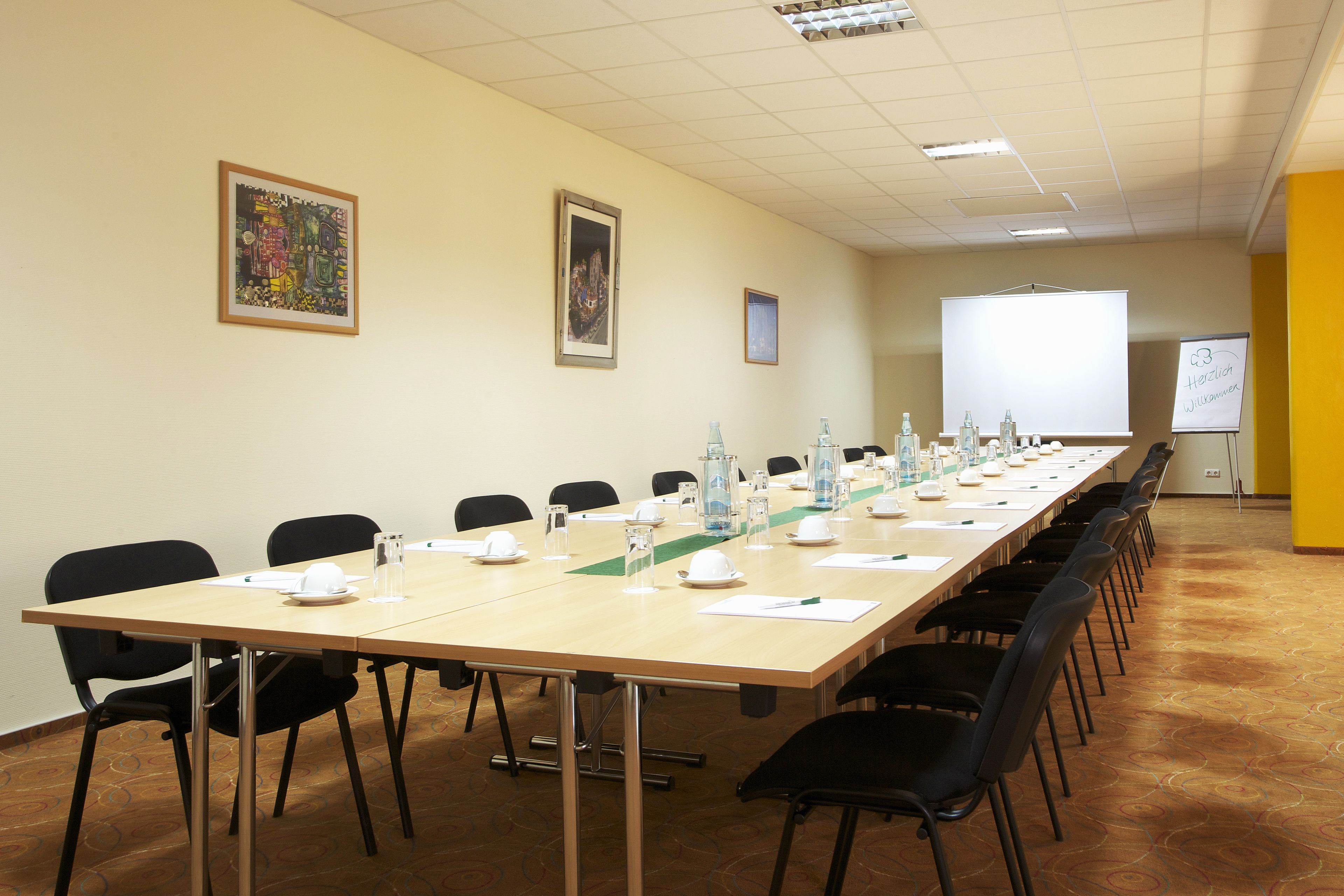 Un salón de conferencias con una larga mesa, sillas y una pizarra.